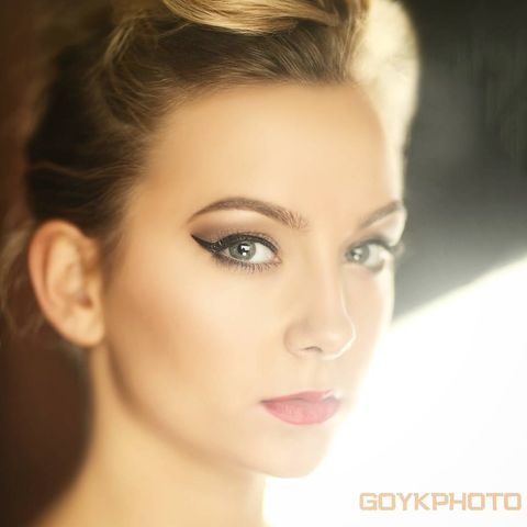 Woman with pulled up dirty blonde hair standing in front of a very bright light source